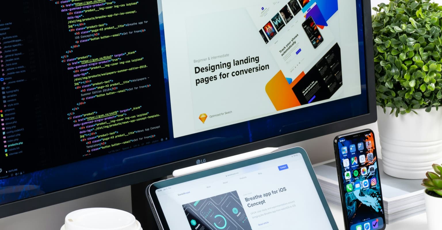 monitor, ipad and phone on desk with code on monitor